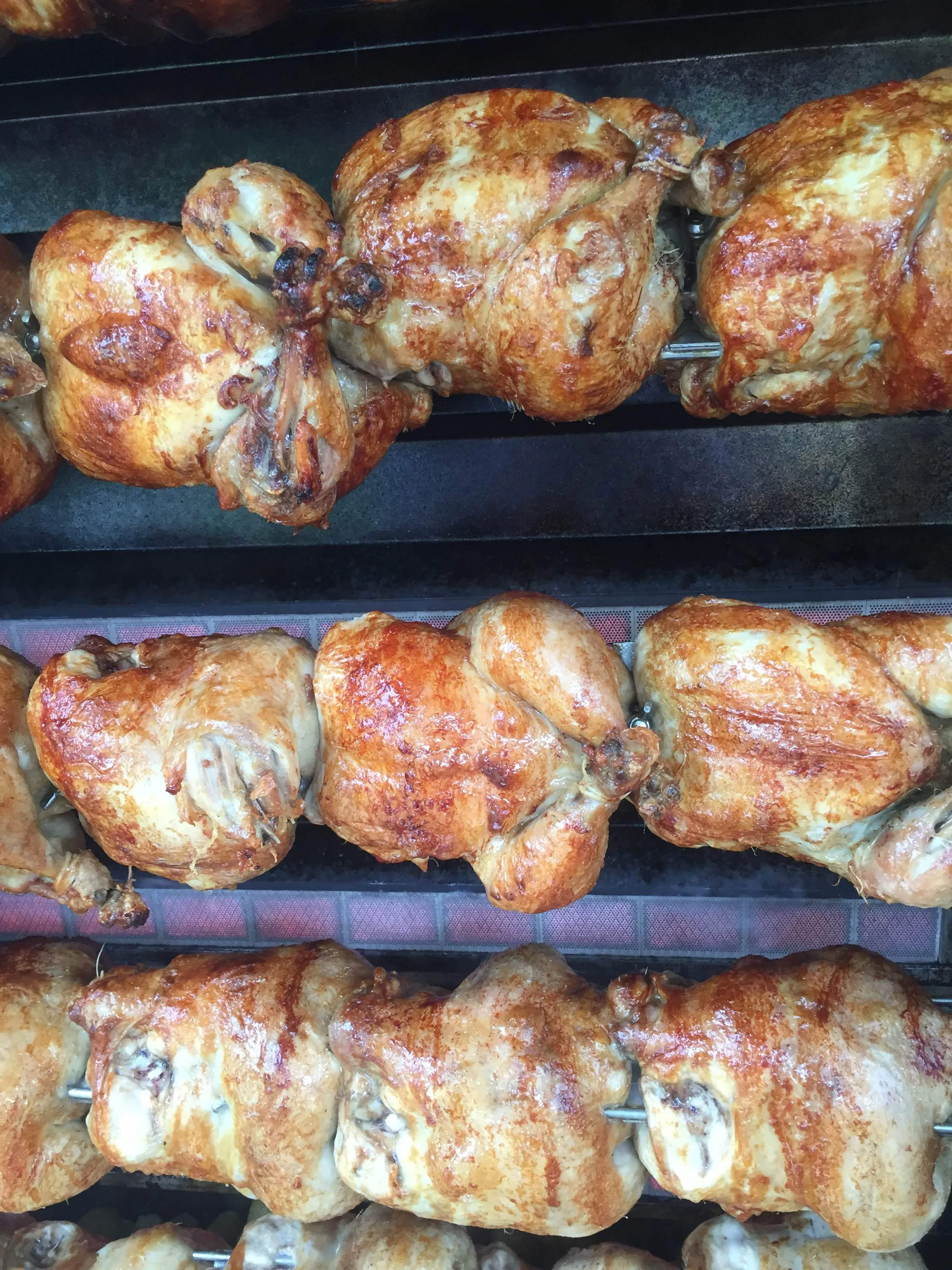 Golden rotisserie chickens spinning on the spit